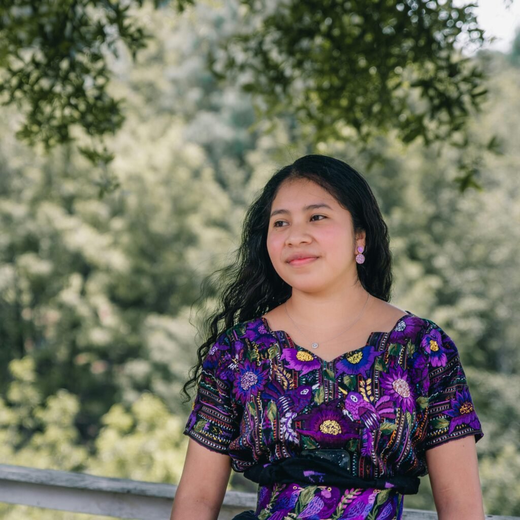 Young woman smiling in traditional attire at a park in Sololá, Guatemala.